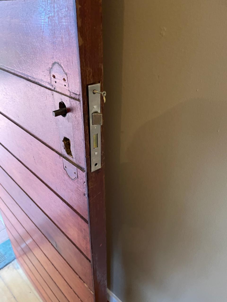 A wooden door with a new mortice lock fitted in its edge and the old handle holes visible.